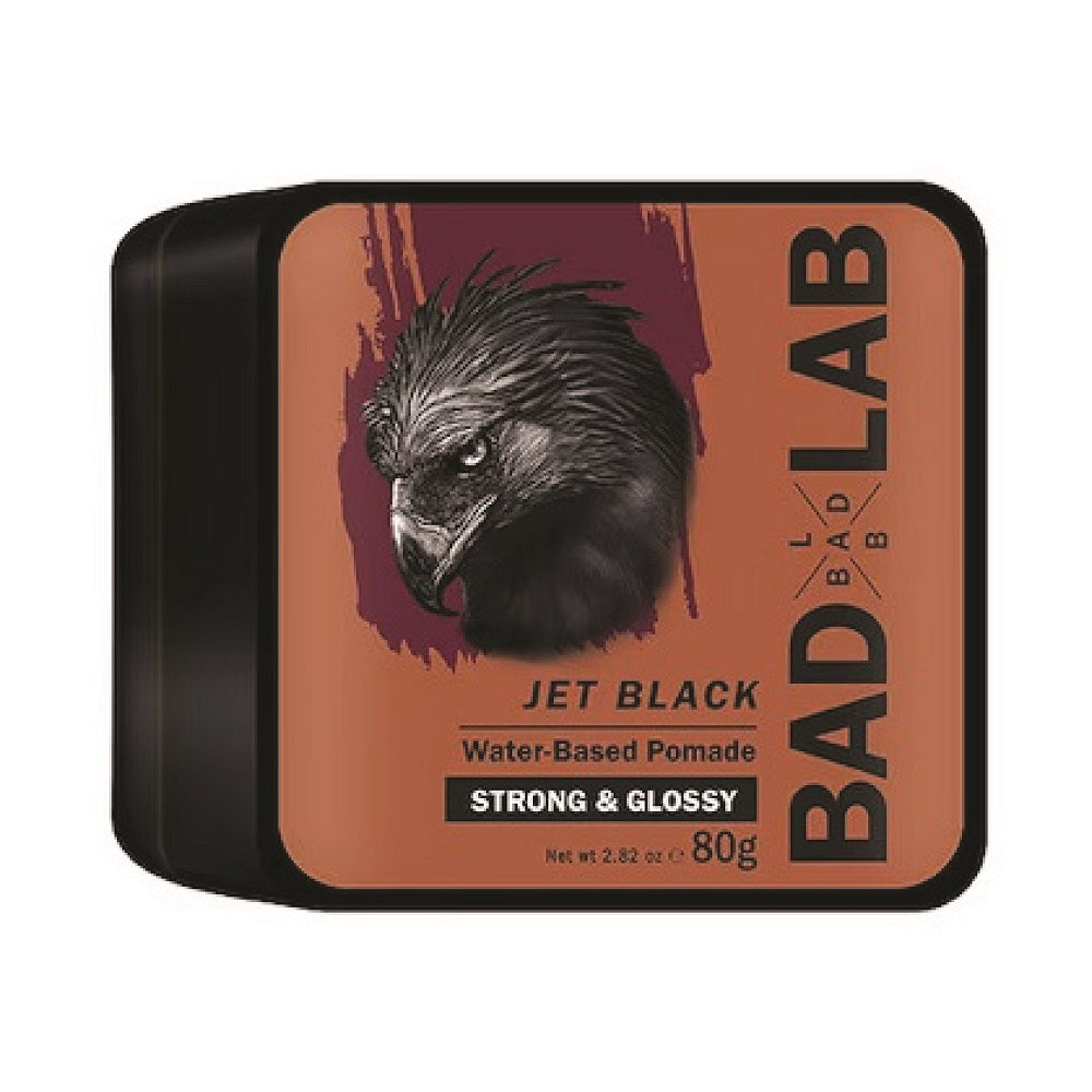 A tin of Bad Lab Jet Black Water-Based Pomade, 80g. The packaging features a black tin with a terracotta orange label displaying a detailed black bird illustration and bold text.