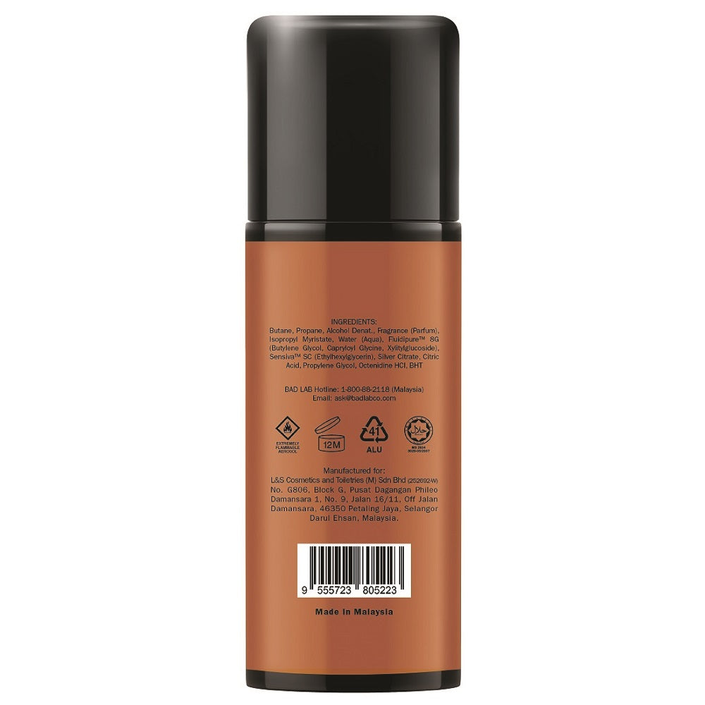 Back view of a cylindrical cosmetic bottle with a black cap and a warm brown label, showing product text, icons, a barcode, and 'Made in Malaysia' on a white background.