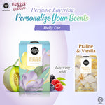Promotional graphic for Good Wines & Cider perfume layering with personalized scents, showing two product boxes: Melon & Berries on the left with melon, berries, and flowers, and Praline & Vanilla on the right with floral artwork. Text reads 'Perfume Layering Personalize Your Scents Daily Use' and 'Layering with'.